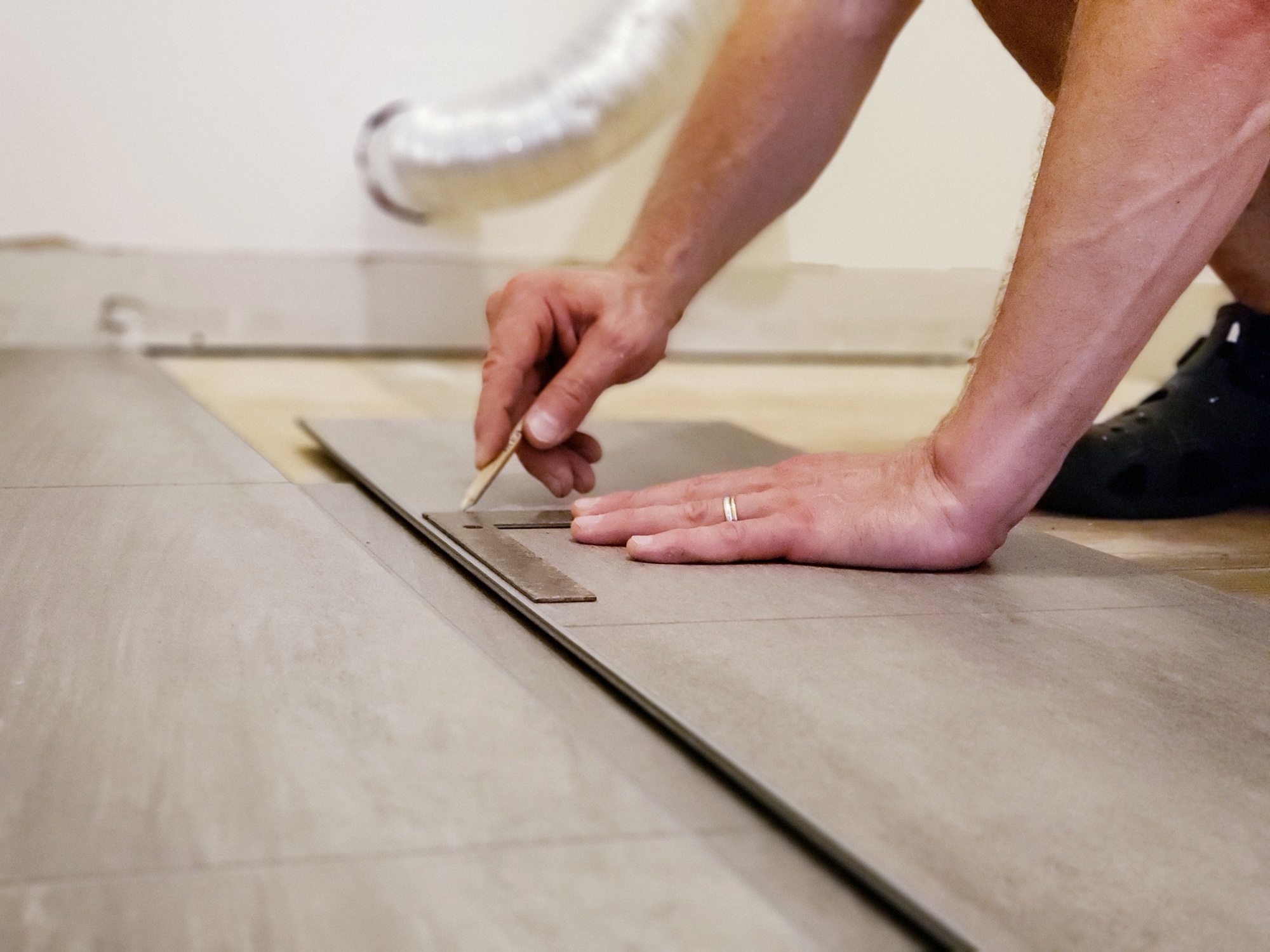 Man's hands holding flooring plank and measuring place to cut for floor installation home improvemen